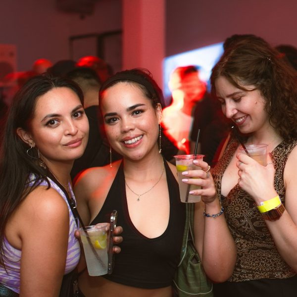 a group of women standing next to each other holding drinks